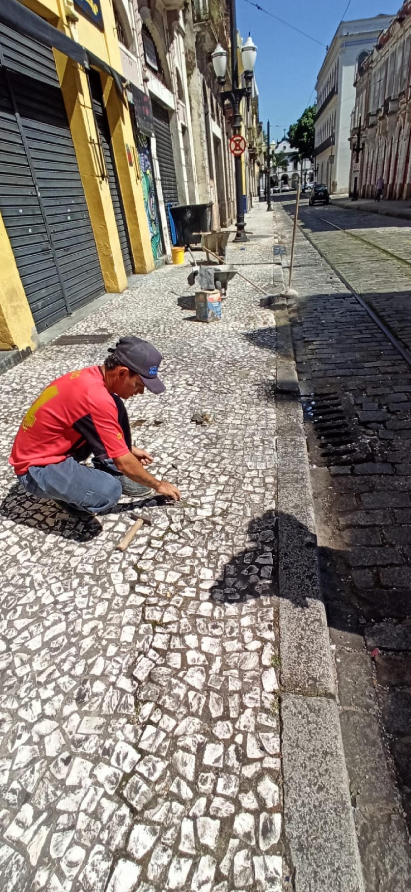 homem está assentando mosaicos em piso. #paratodosverem