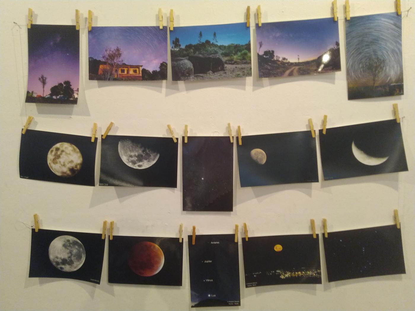 Imagens fixadas em parede mostram lugares e a lua em vários ângulos. #Pracegover