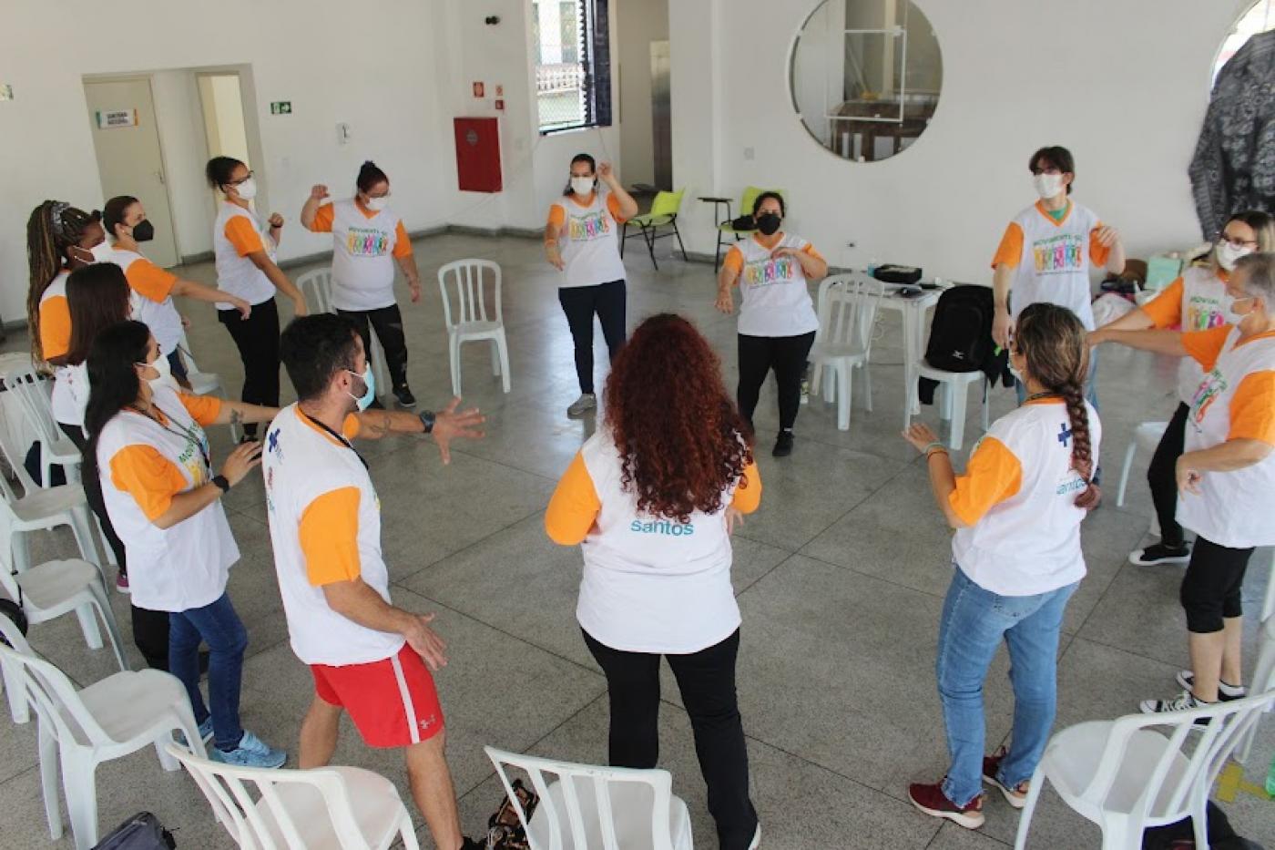 grupo de pessoas uniformizadas está em pé em roda. eles fazem movimentos com os braços. #paratodosverem