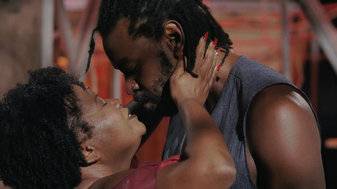 casal de negros se aproxima face a face como se fossem se beijar na boca. #paratodosverem 