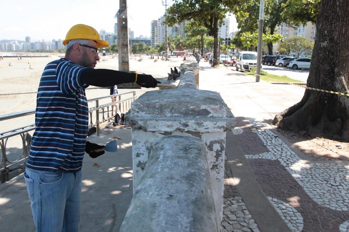 homem pinta mureta. Ele usa capacete e luva. #paratodosverem