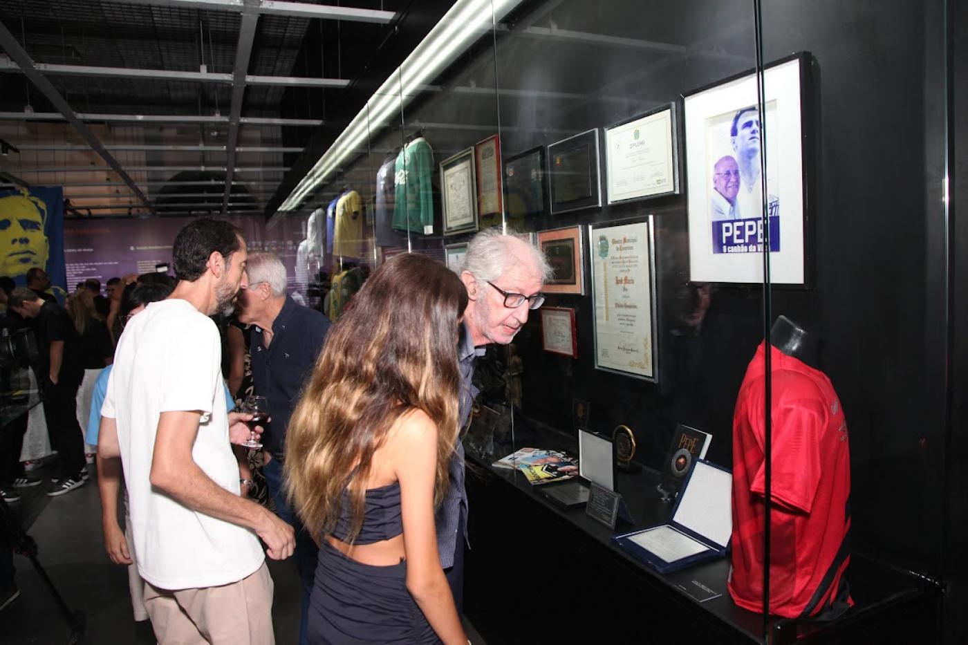 pessoas olhando exposição no museu pelé #paratodosverem 