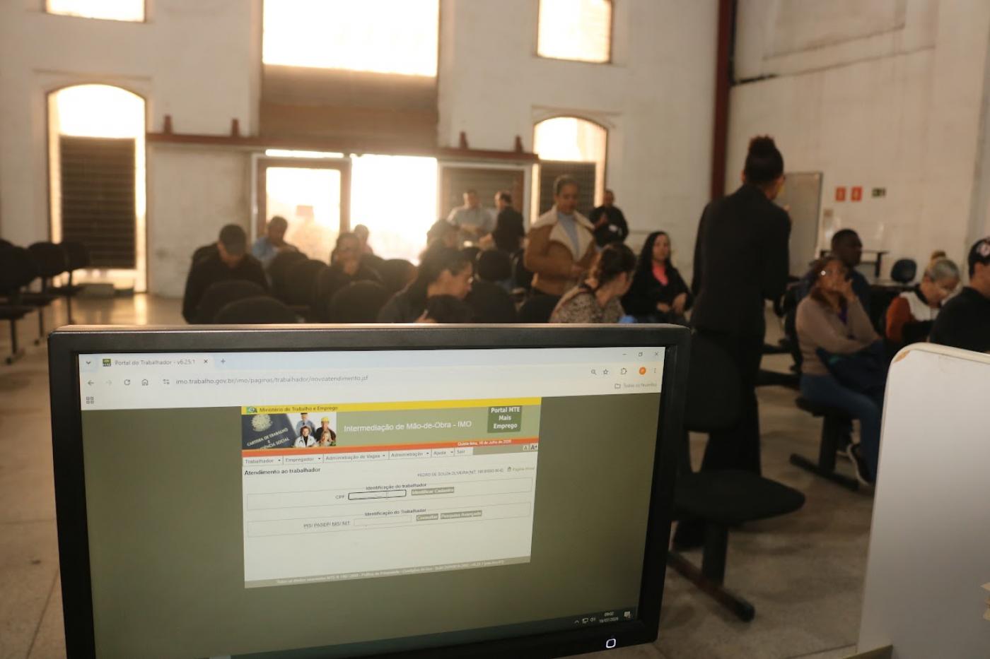 computador na frente de pessoas esperando atendimento #paratodosverem 