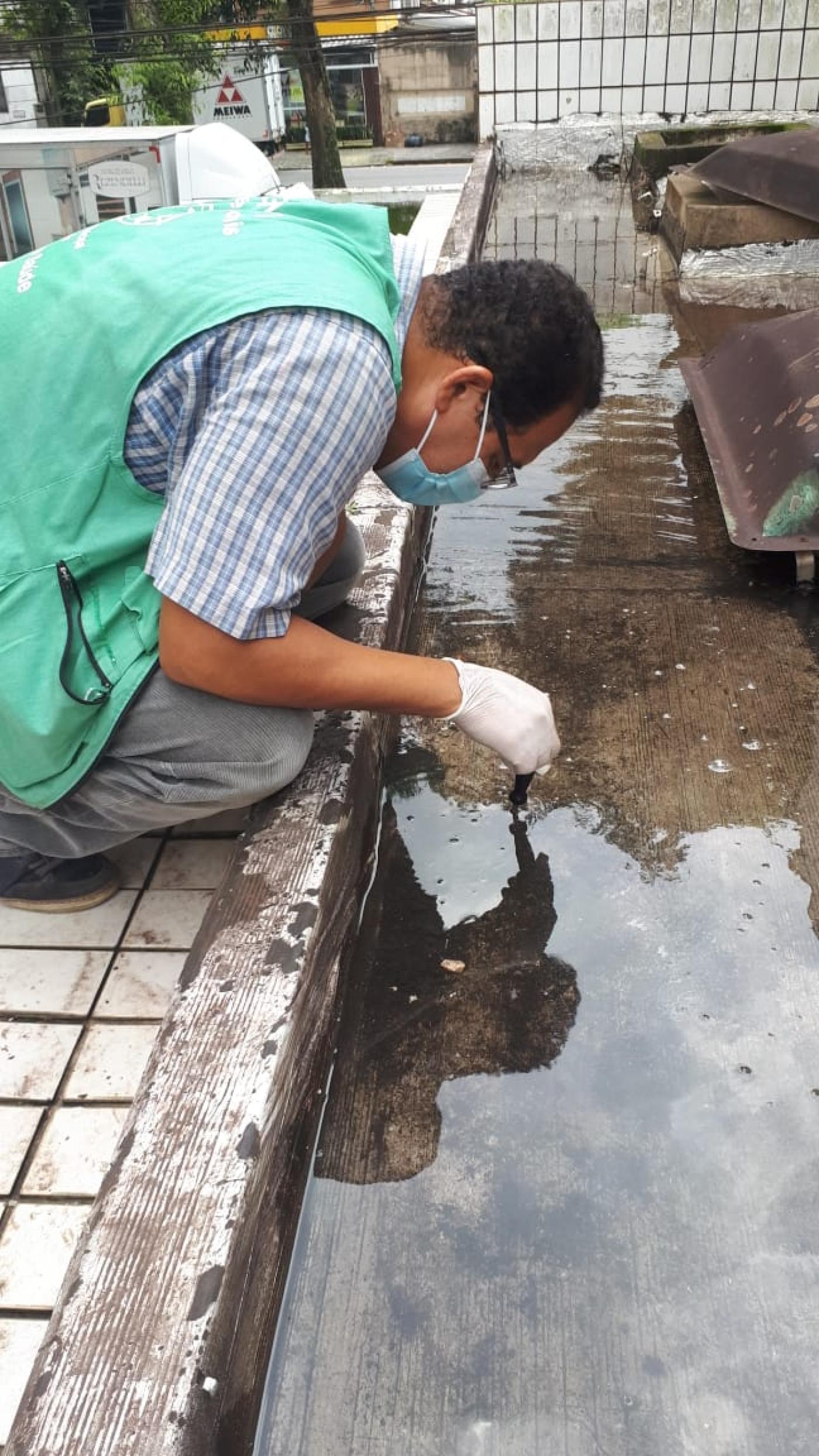 agente fiscaliza laje com água acumulada. #paratodosverem