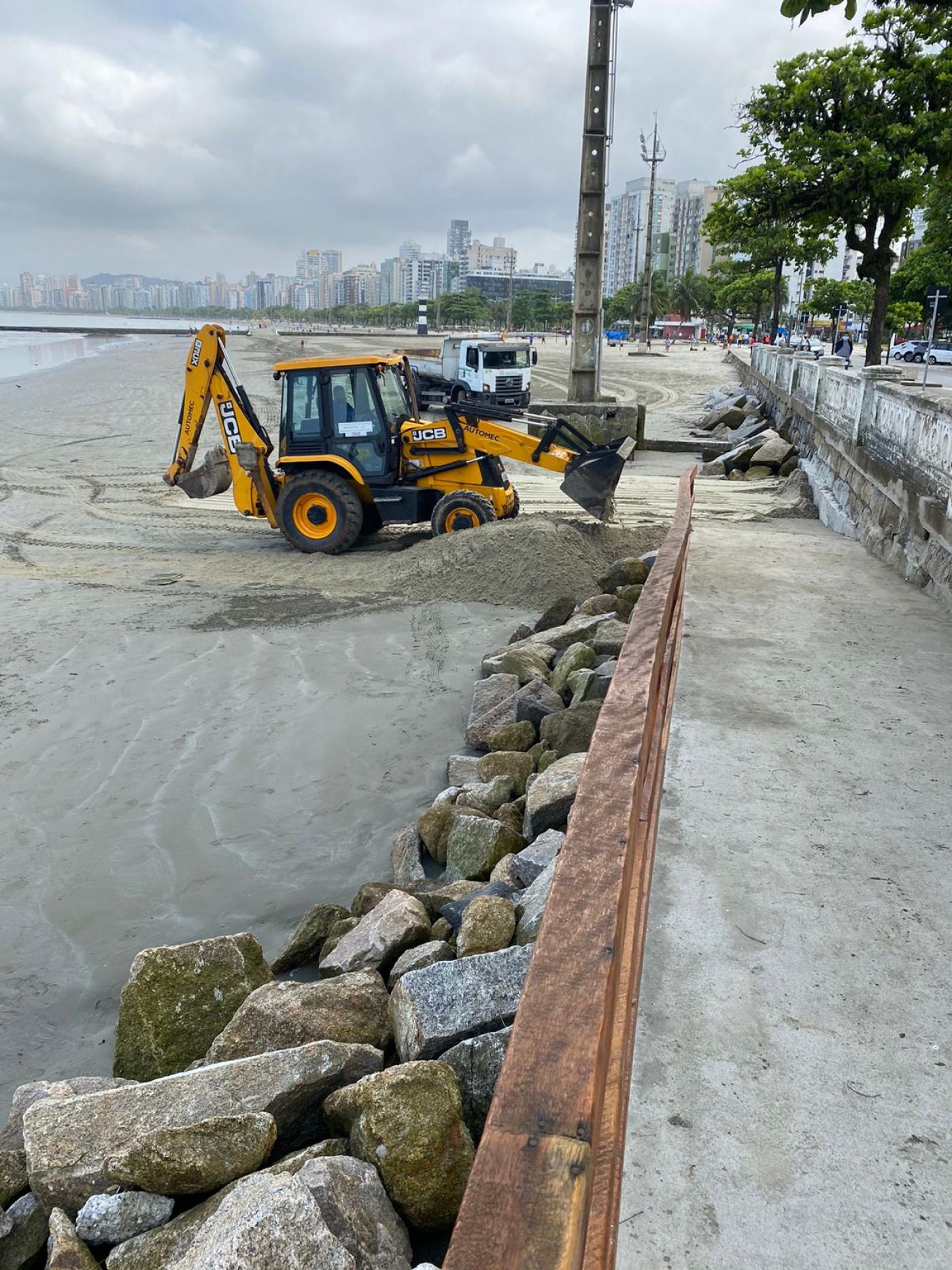 trator leva areia para trecho de ponta da praia. Enrocamento em primeiro plano. #paratodosverem