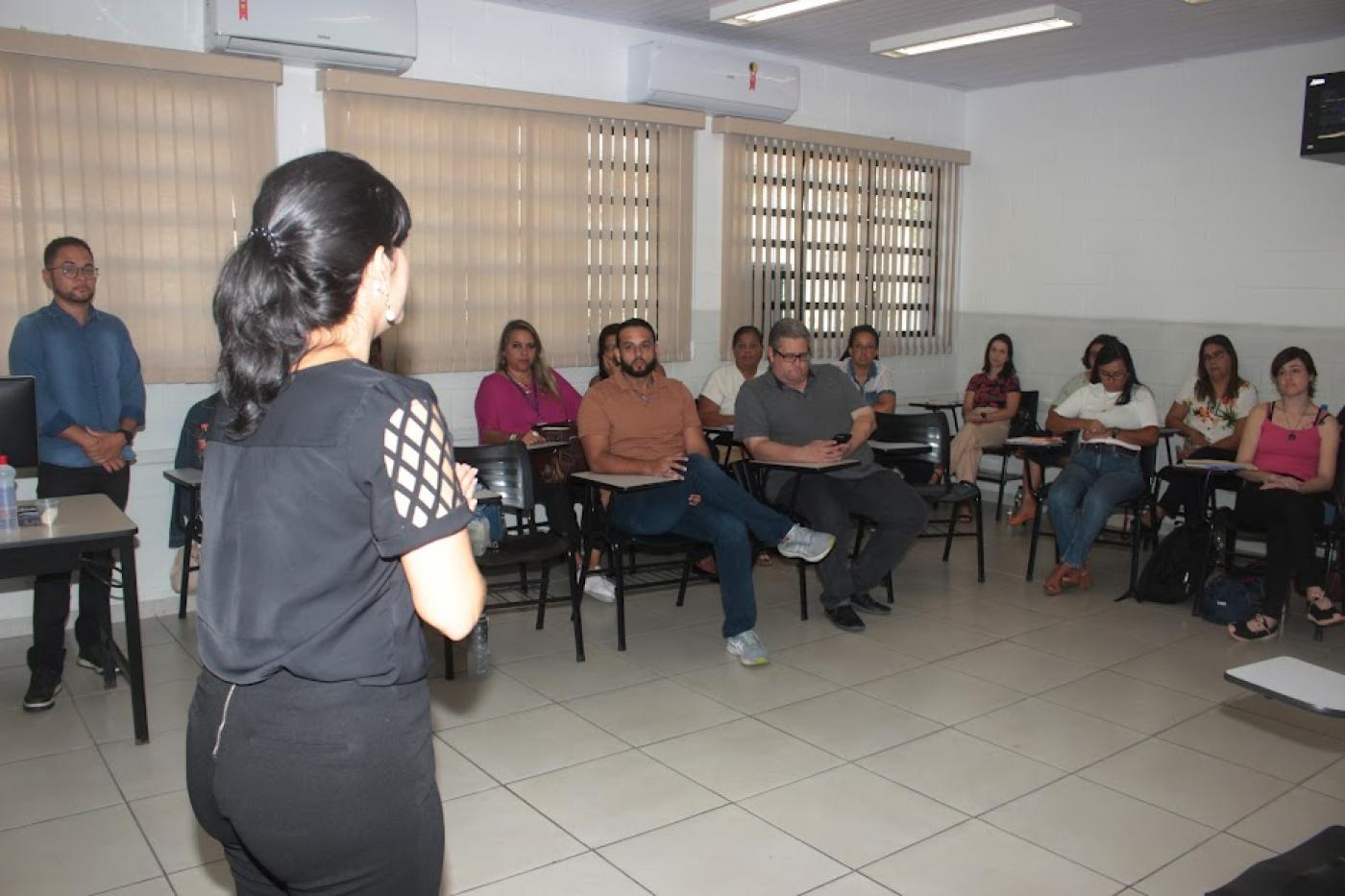 pessoas estão sentadas em sala assistindo a uma palestra. #paatodosverem