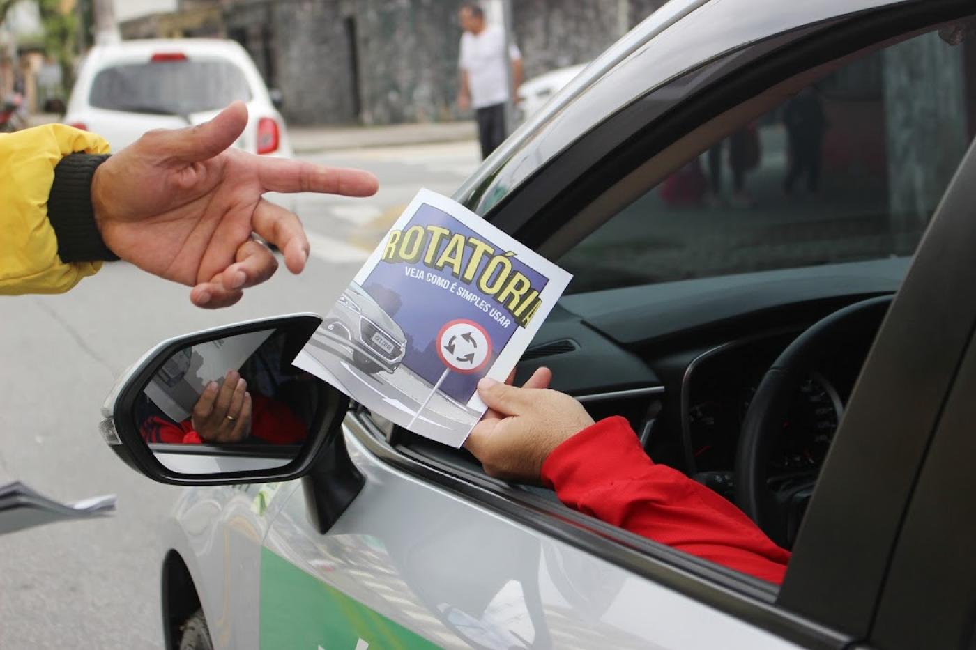 pessoa dentro do carro segura panfleto #paratodosverem