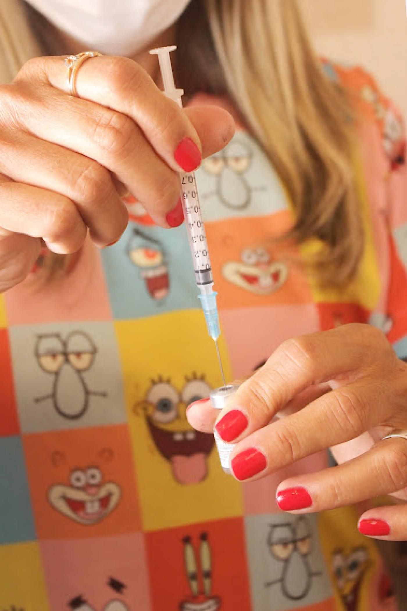 close de mulher segurando seringa e frasco de vacina. #paratodosverem