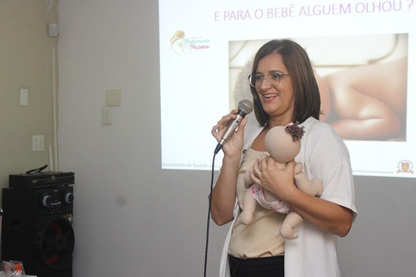 mulher segura boneca de tecido e faz simulação dela contra o seio. #paratodosverem