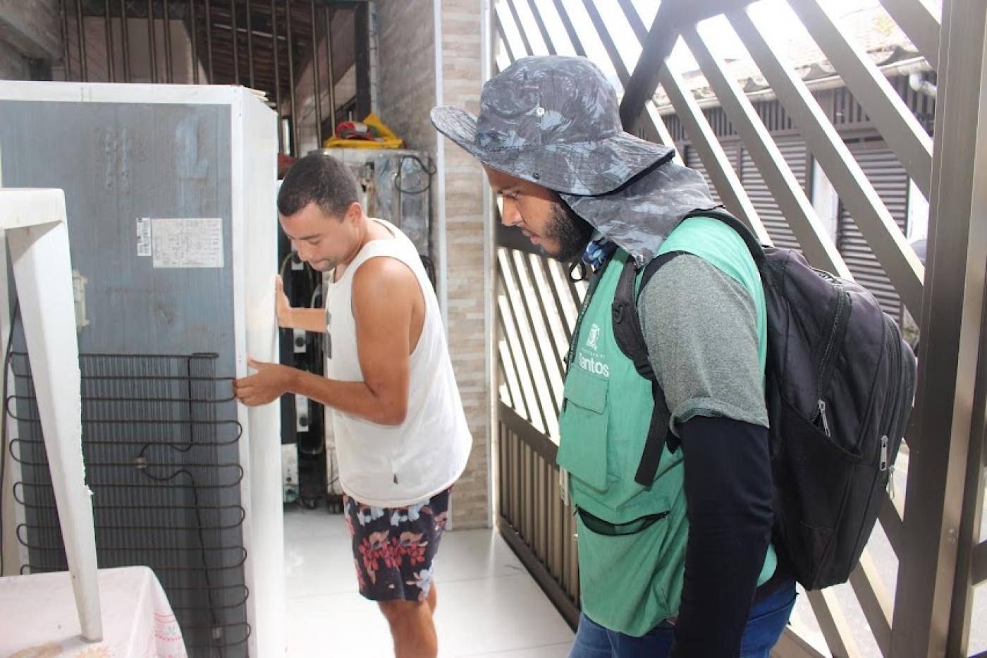 agente olha para geladeira que está sendo arrastada pelo dono. #paratodosverem