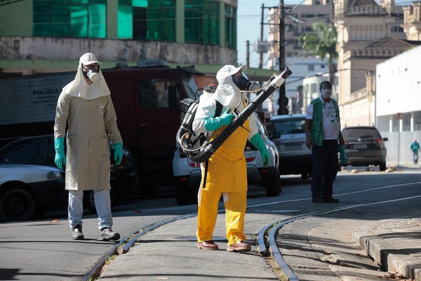 Um homem faz aplicação de inseticida e outro o acompanha. #Paratodosverem