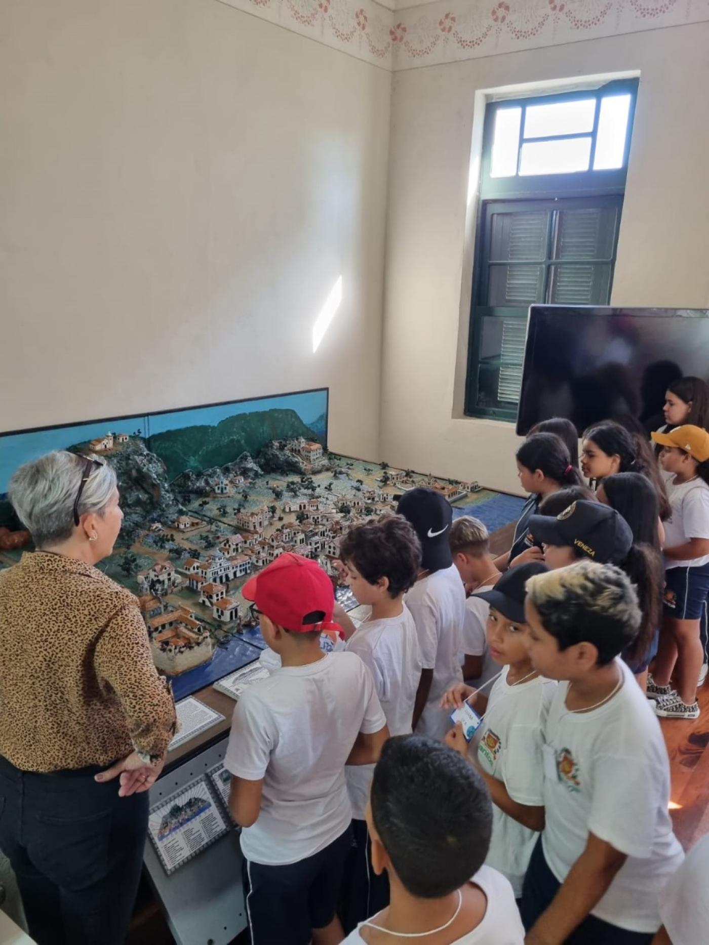 crianças observam maquete. #paratodosverem