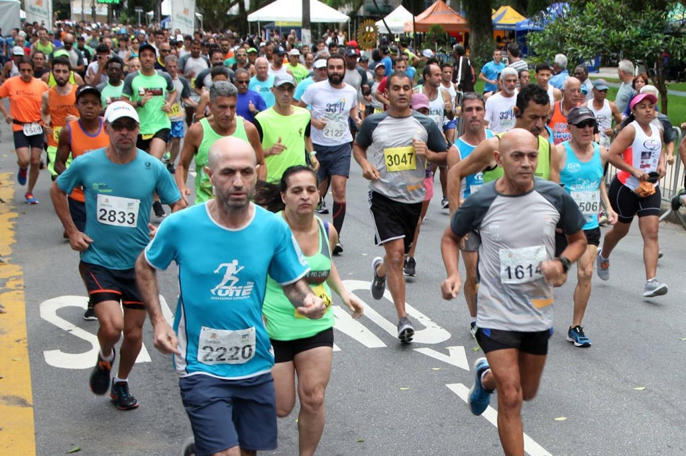 Atletas correm em avenida durante competição. #paratodosverem