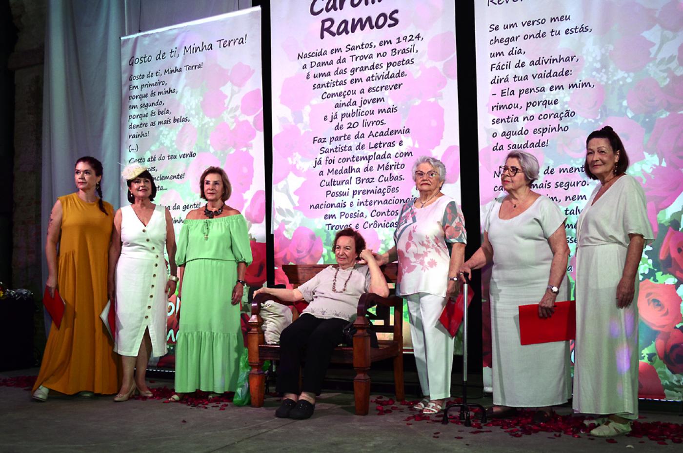 poetas estão em pé à frente de grandes banners com poesias impressas. #paratodosverem