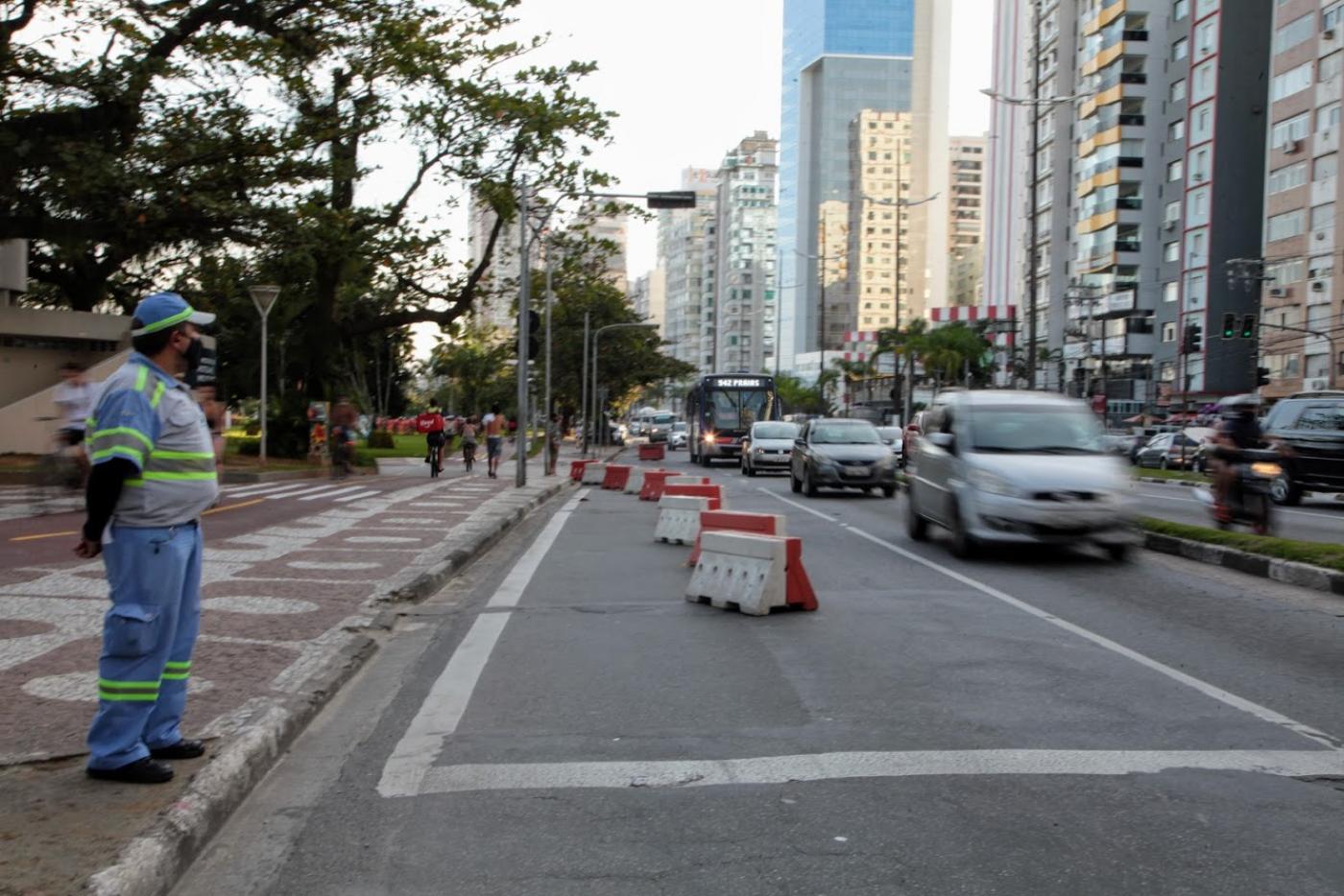 trecho de via interditado com blocos. Carros passam um uma faixa. Agente da CET monitora o trânsito. #paratodosverem