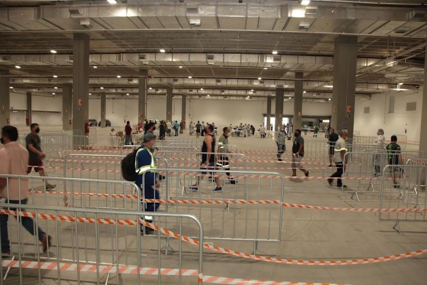 Espaço interno do Santos Convention Center com portuários circulando. #paratodosverem