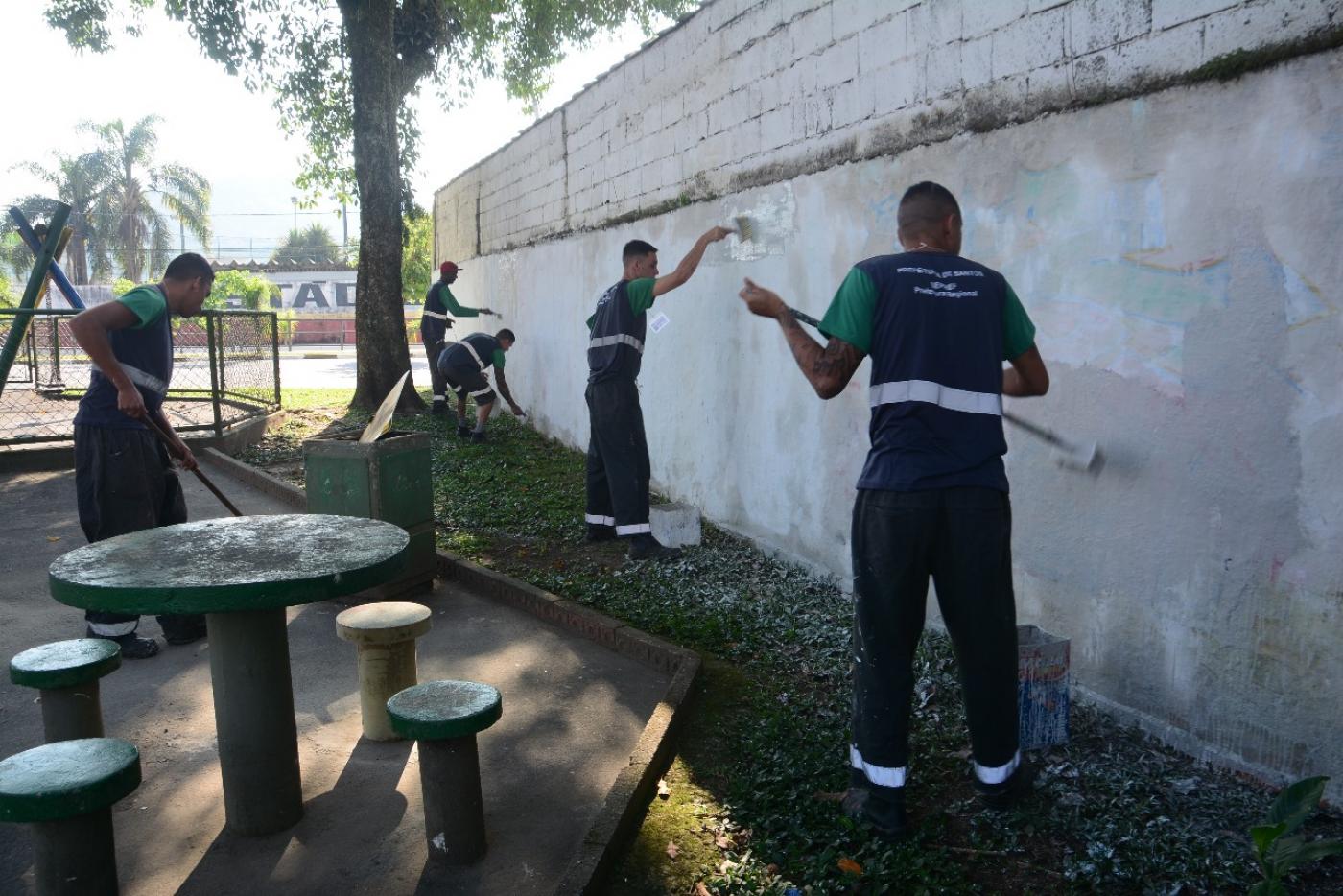 homens pintam muro em praça. #paratodosverem