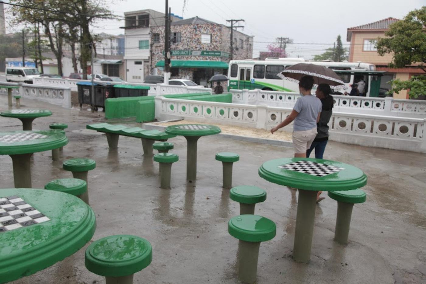 Praça com mesas de dama e canal com muretas. #paratodosverem