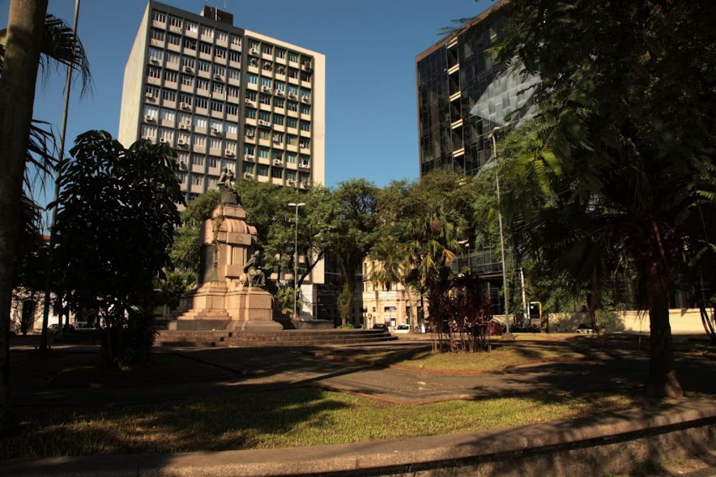 vista geral da praça barão do rio branco, com monumento ao centro e vegetação nas 