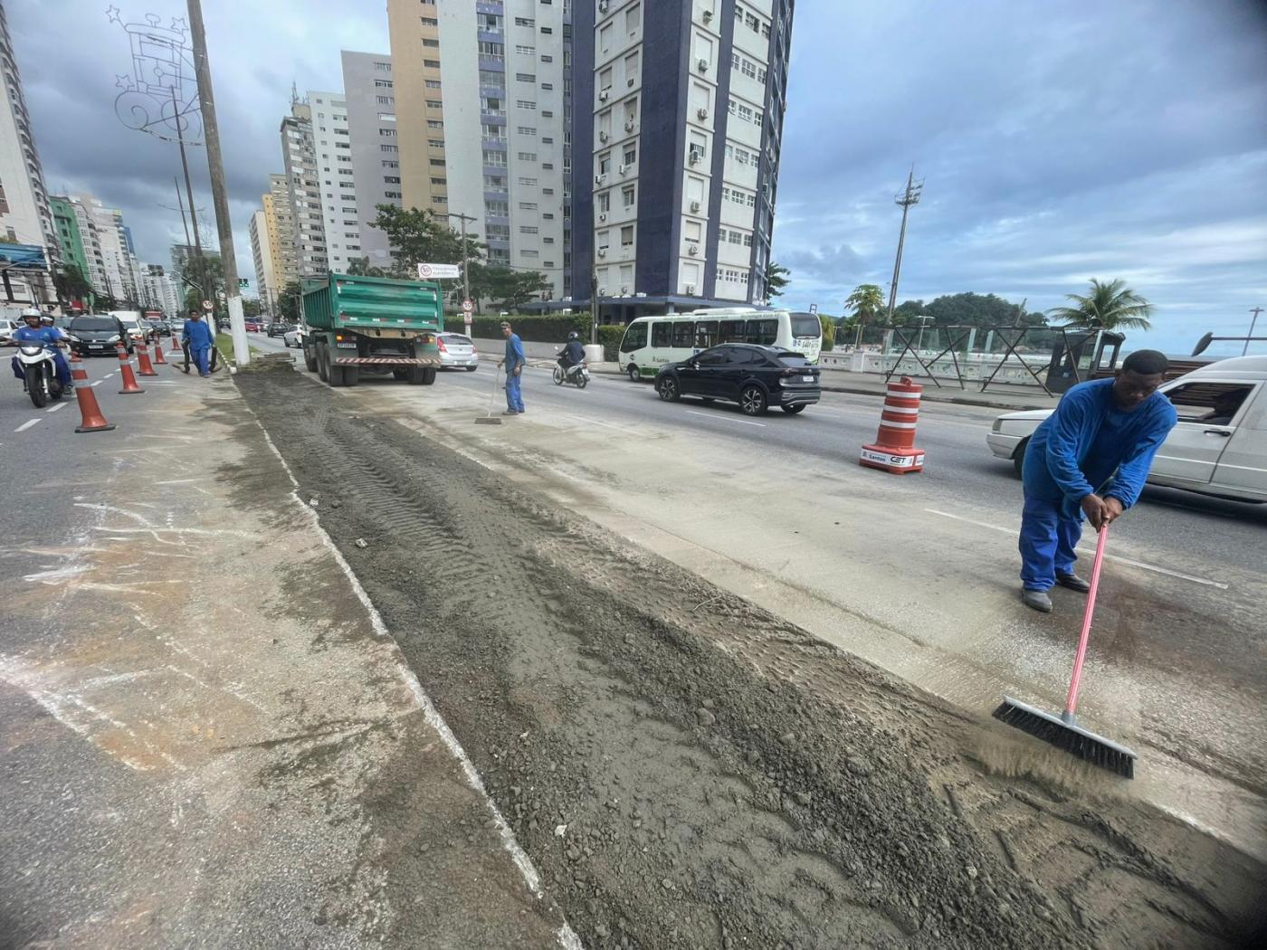 canteiro central de avenida com caminhào ao fundo. a área está delimitada por cones. Há um homem trabalhando na obra, ao lado direito da imagem. #paratodosverem 