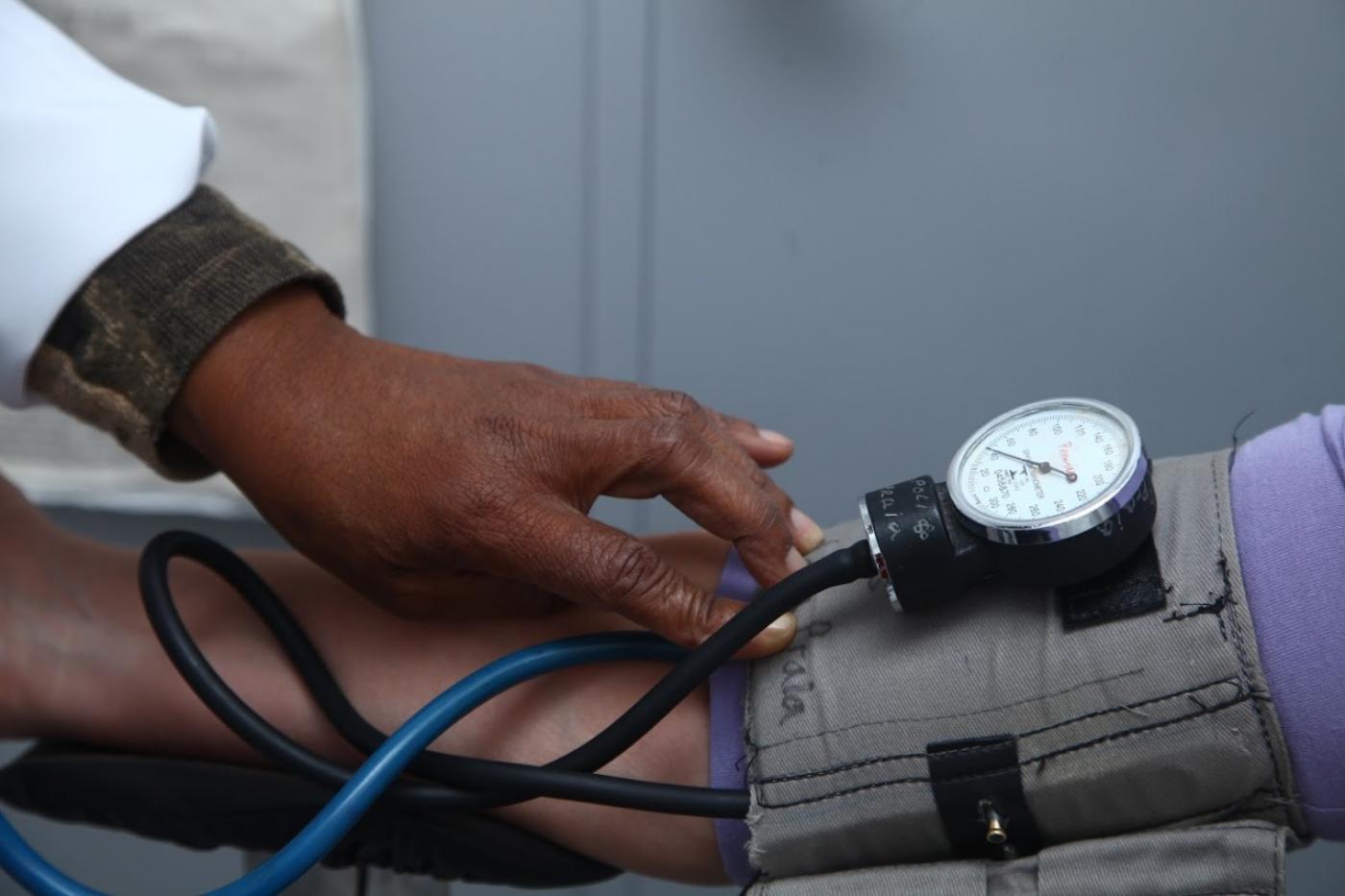 imagem em close de pessoa tendo a pressão arterial medida por outra. #paratodosverem