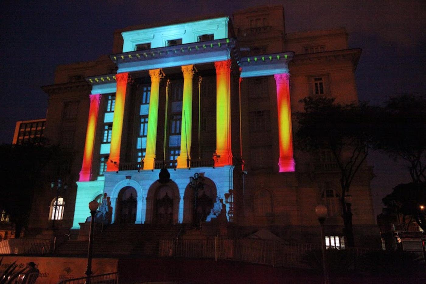 a fachada da prefeitura à noite com projeção colorida. #paratodosverem