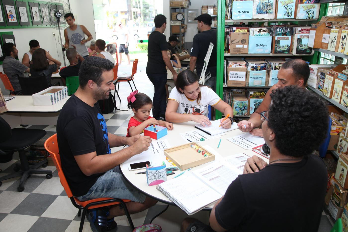 pessoas em mesa na gibiteca #paratodosverem