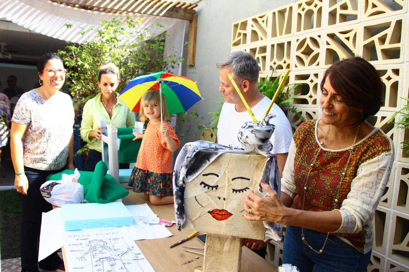 Oficina de mamulengos. Em primeiro plano aparece um boneco de papelão com cara de mulher. #Pracegover