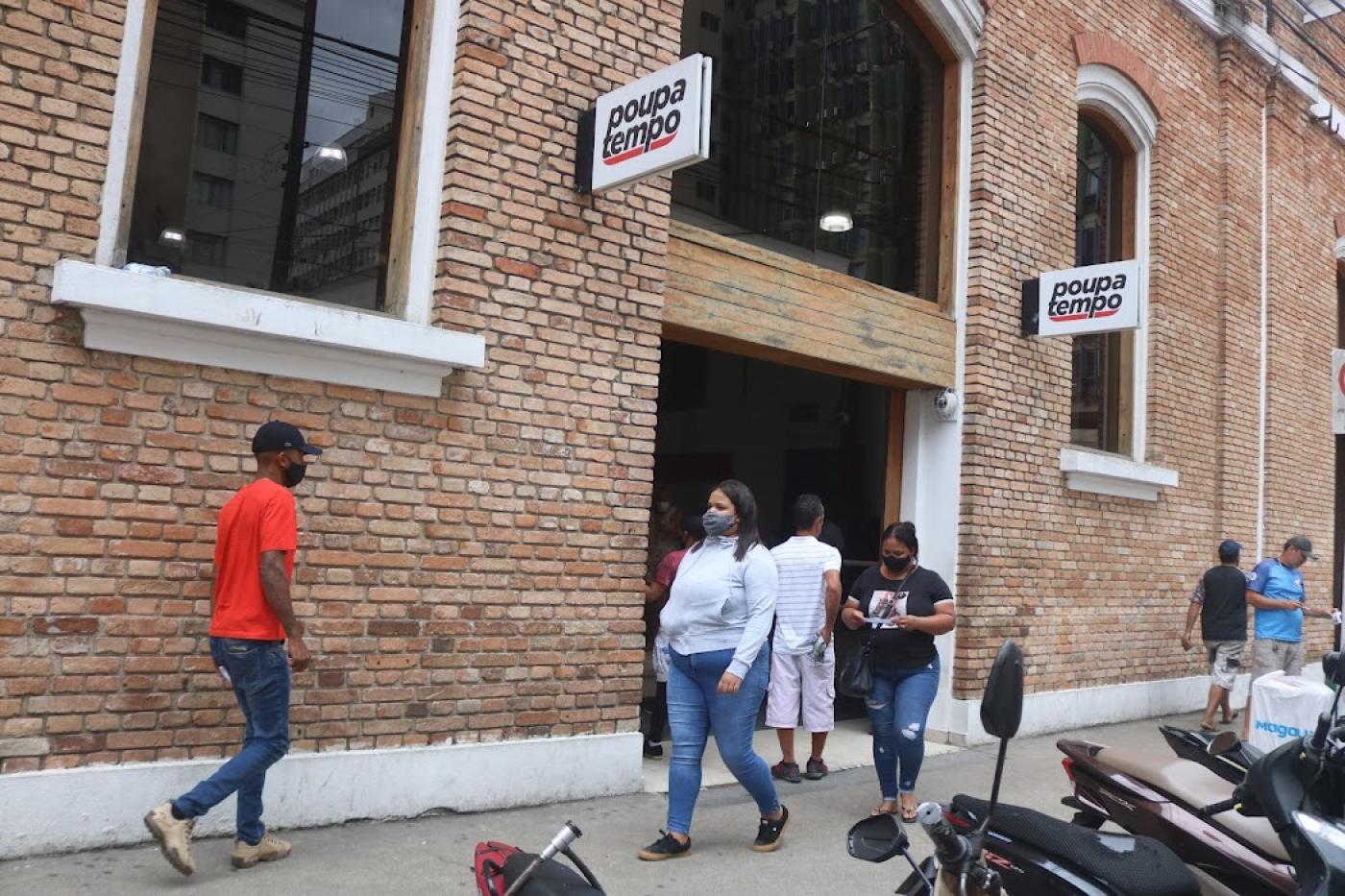 entrada do poupatempo com várias pessoas circulando na calçada #paratodosverem