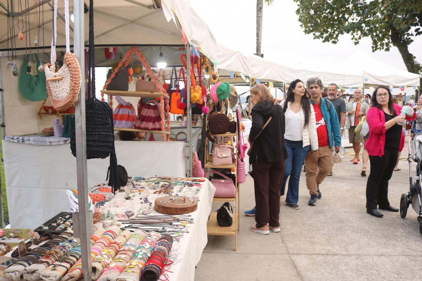 pessoas circulam por barracas de artesanato. #paratodosverem