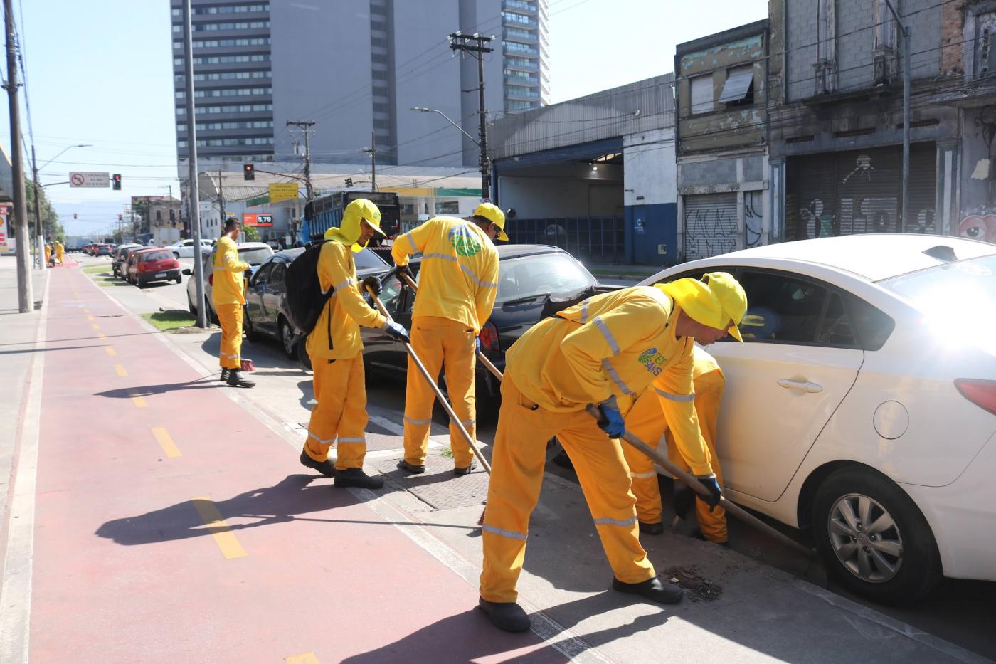 homens varrem guia de calçada. #paratodosverem 