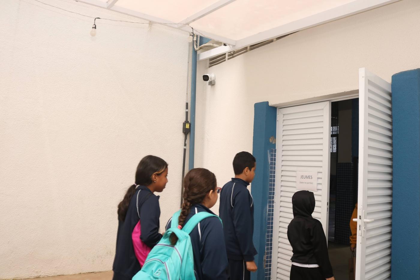alunos entram em sala. no alto da parede há uma câmera. #paratodosverem
