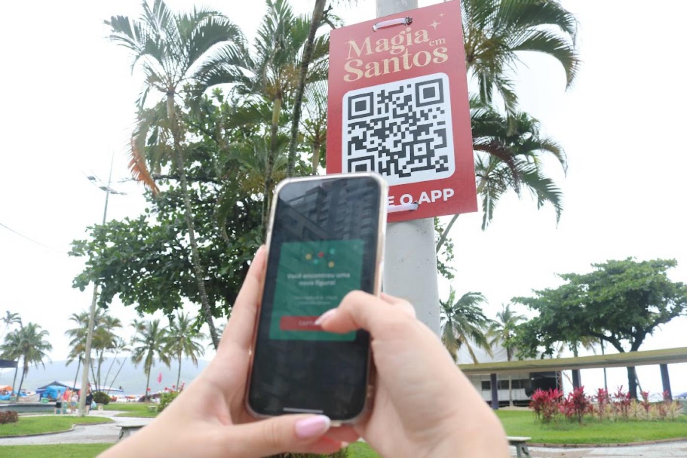 pessoa aponta celular para poste com QR code #paratodosverem