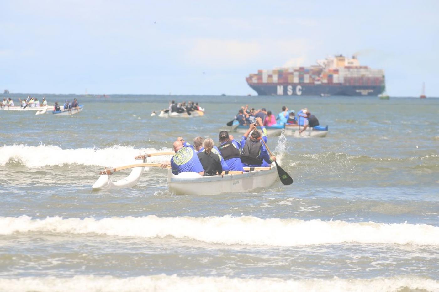 canoa havaiana no mar com diversos remadores empurrando 