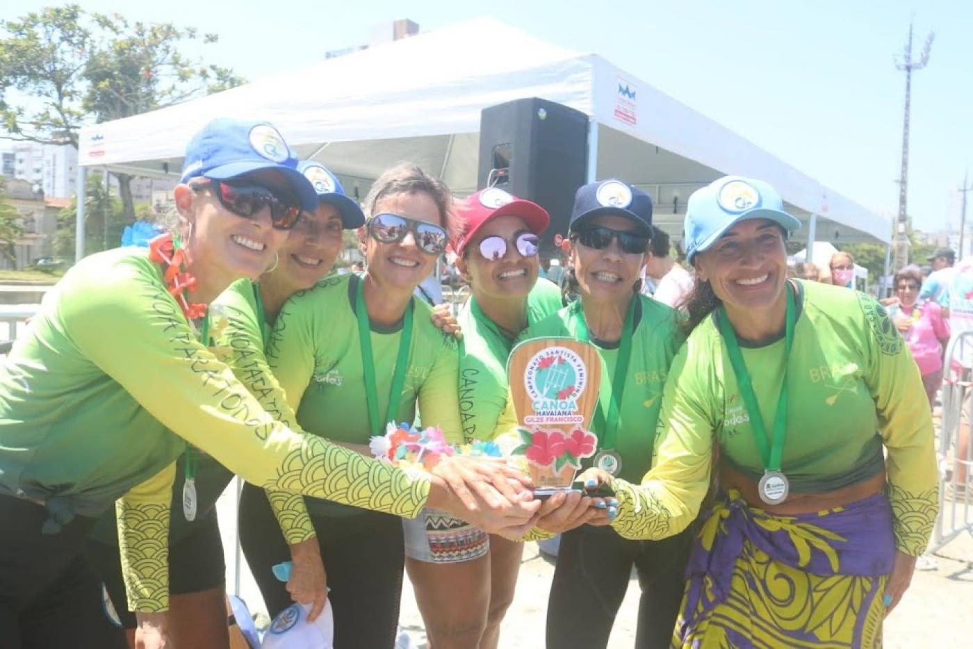 seis mulheres posam para foto sorrindo e segurando troféu ao mesmo tempo. #paratodosverem