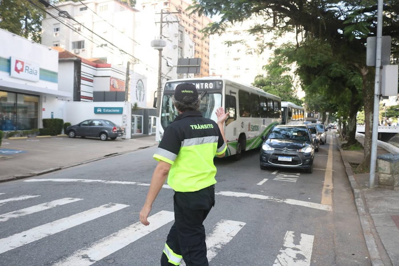 agente de trânsito gesticula para veículos na rua. #paratodosverem 