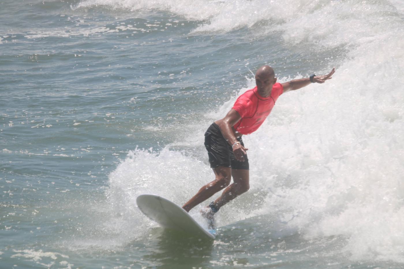 surfista equilibra-se em cima de uma prancha de longboard #paratodosverem