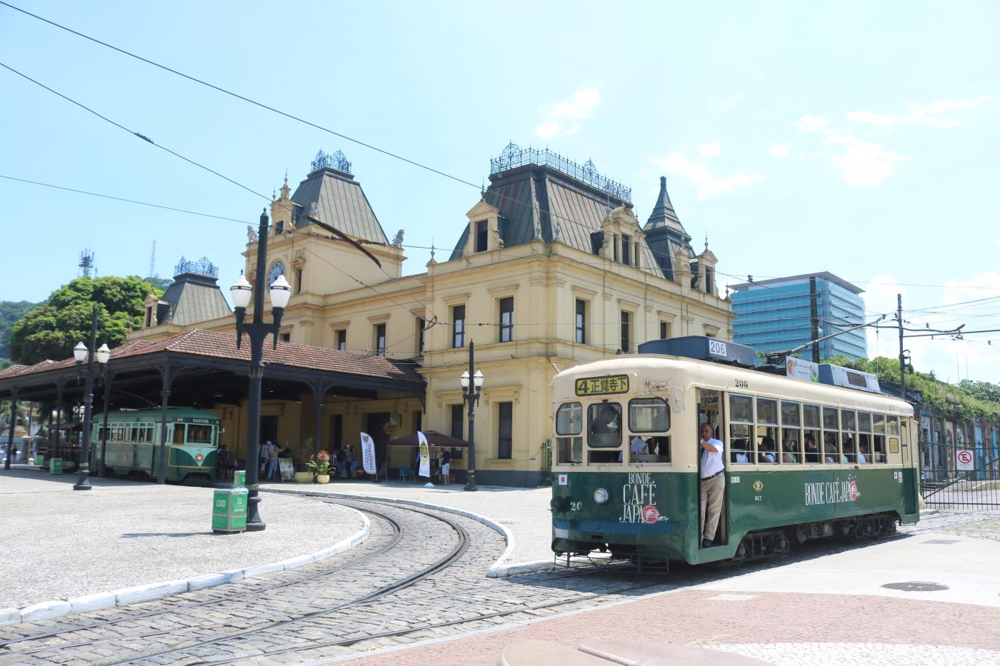 imagem mostra passagemd o bonde Japão com Estação do Valongo ao fundo #paratodosverem