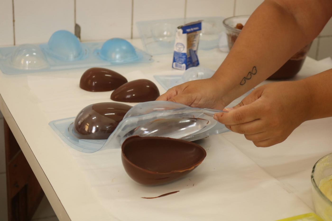 mãos desenformam ovo de chocolate. #paratodosverem 