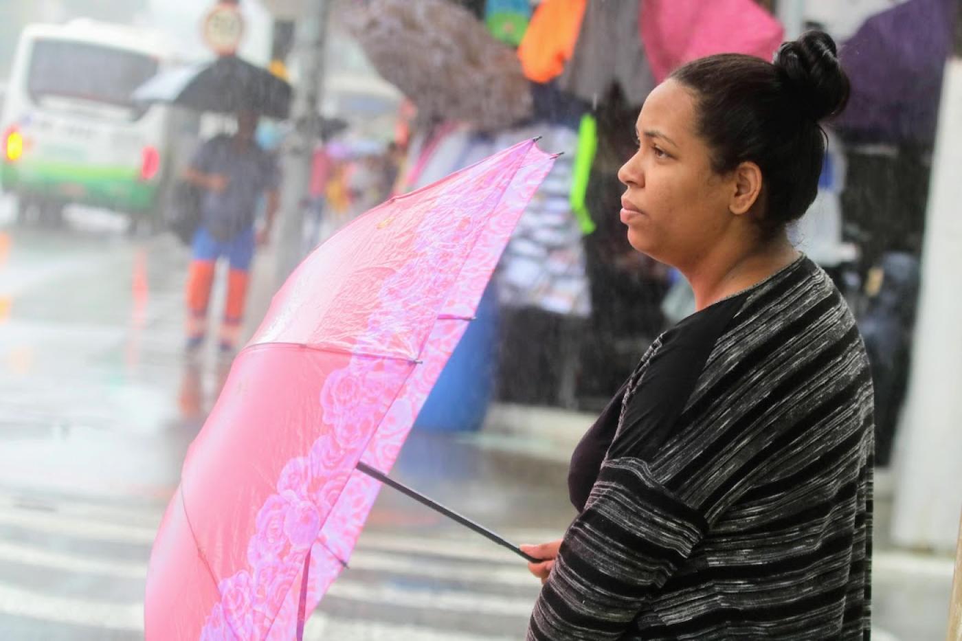 mulher segurando guarda chuva olha para frente em dia chuvoso #paratodosverem