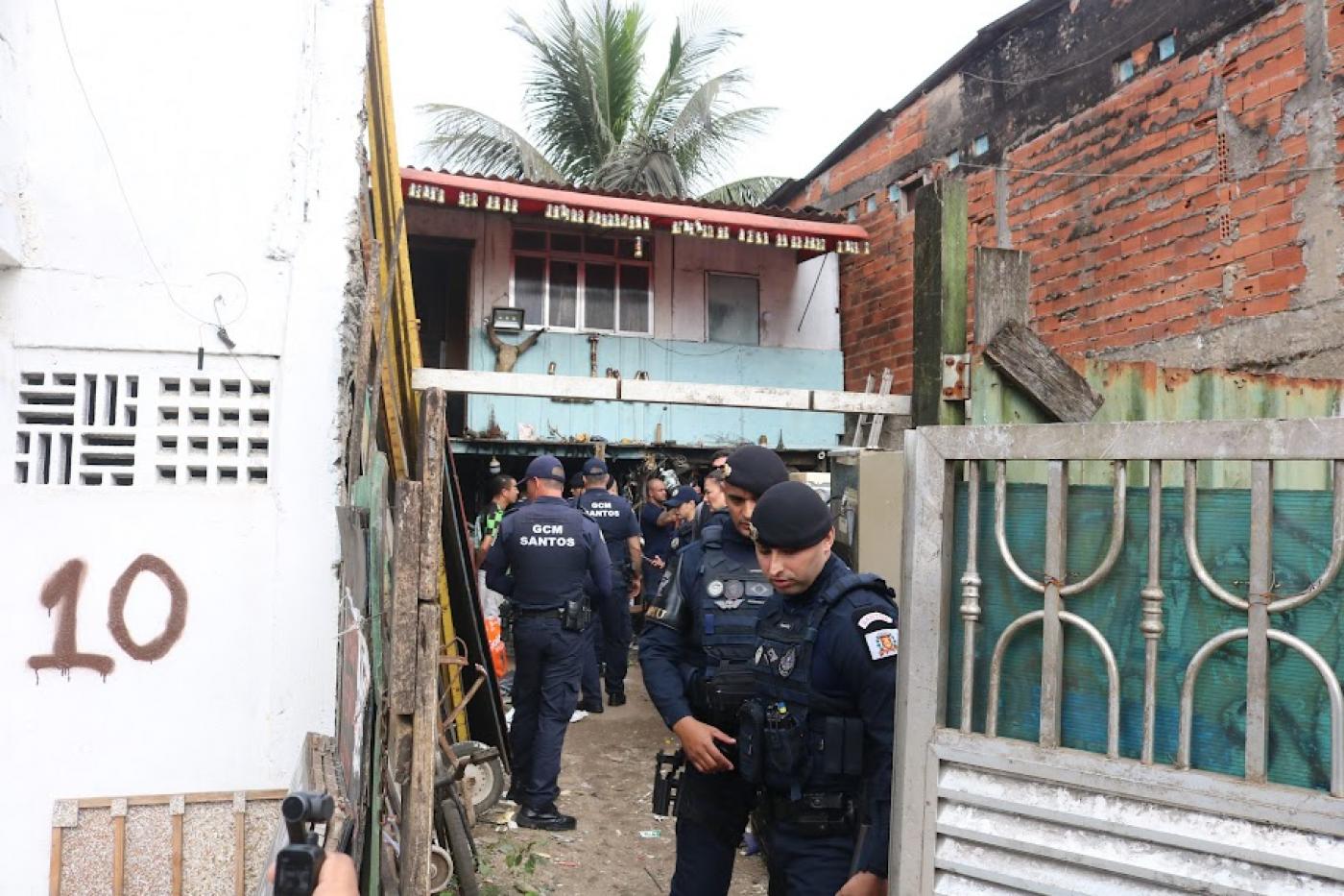 guardas municipais estão na entrada de um ferro-velho. #paratodosverem 