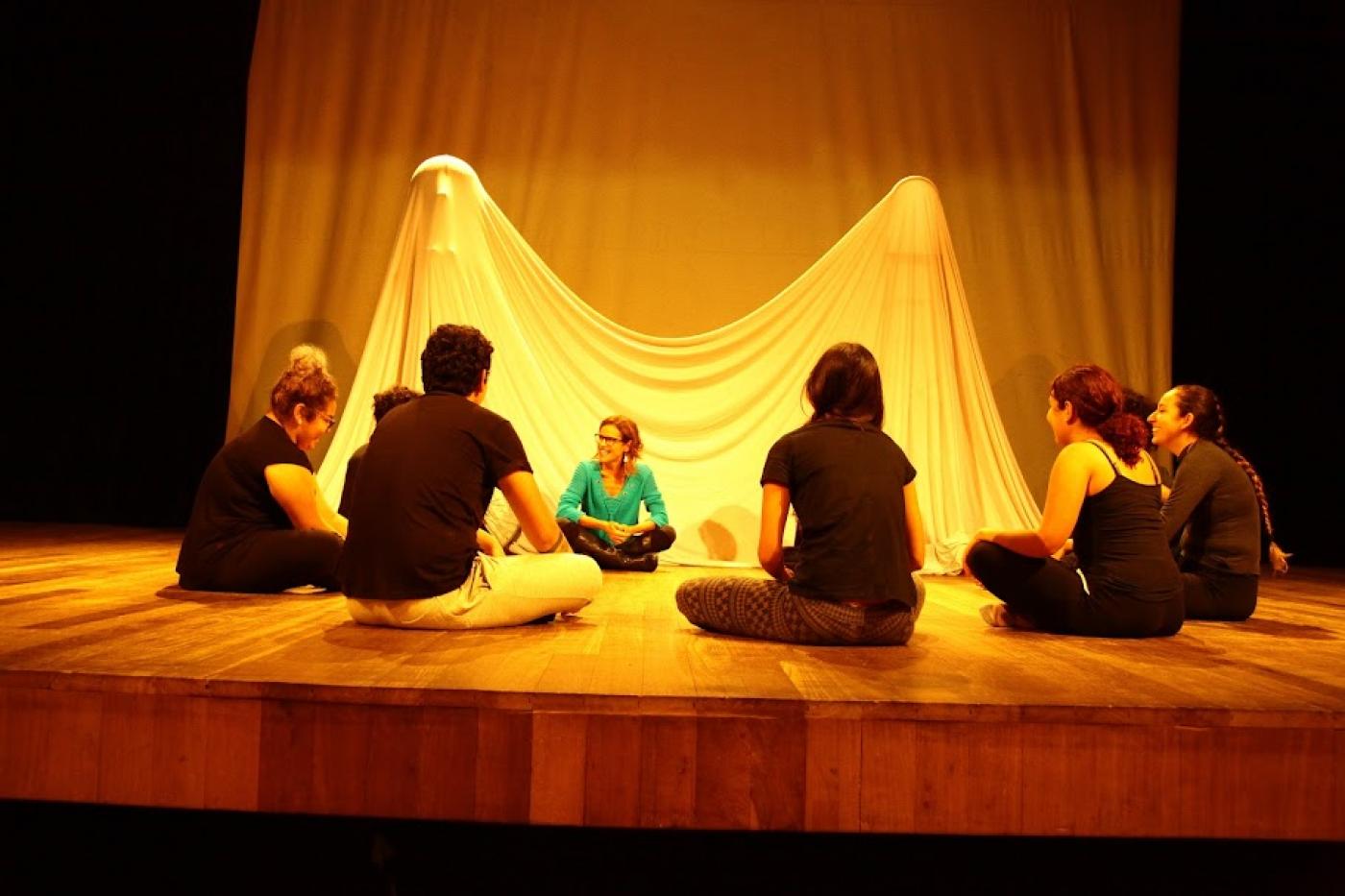 alunos de teatro estão sentado no palco conversando. #paratodosverem 