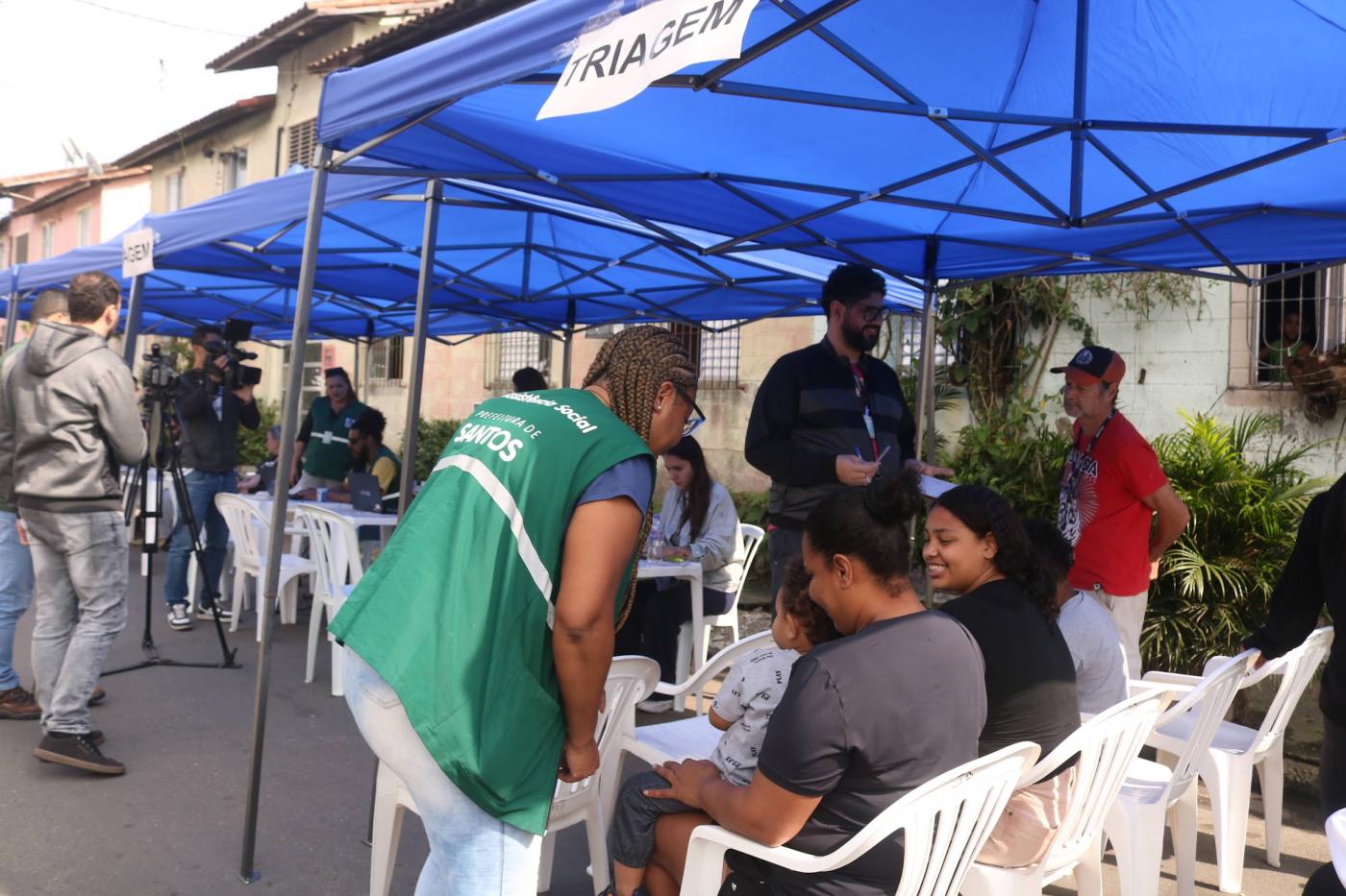agente uniformizada atende pessoas sob tenda de triagem. #paratodosverem 