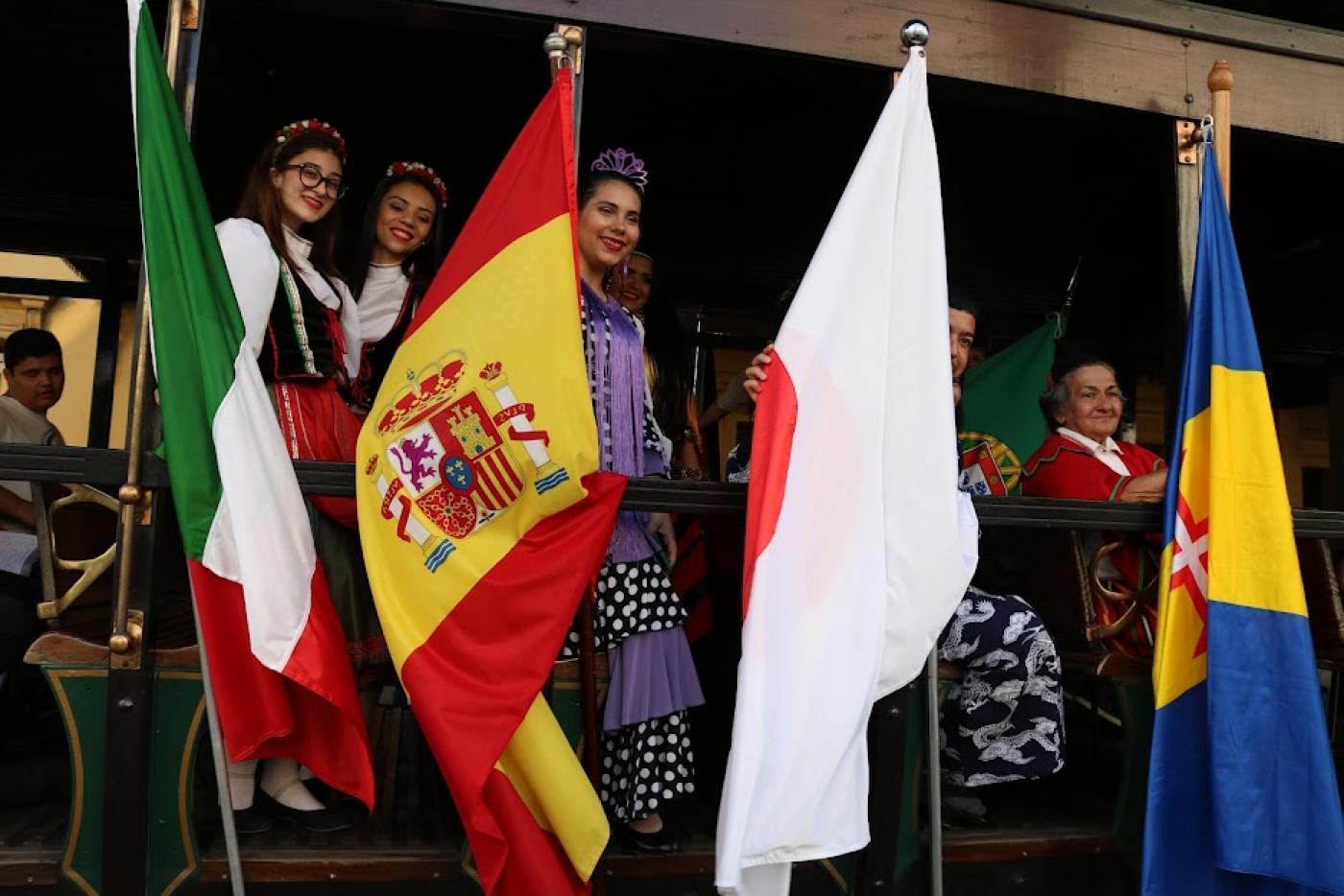 mulheres seguram bandeiras de vários países #paratodosverem