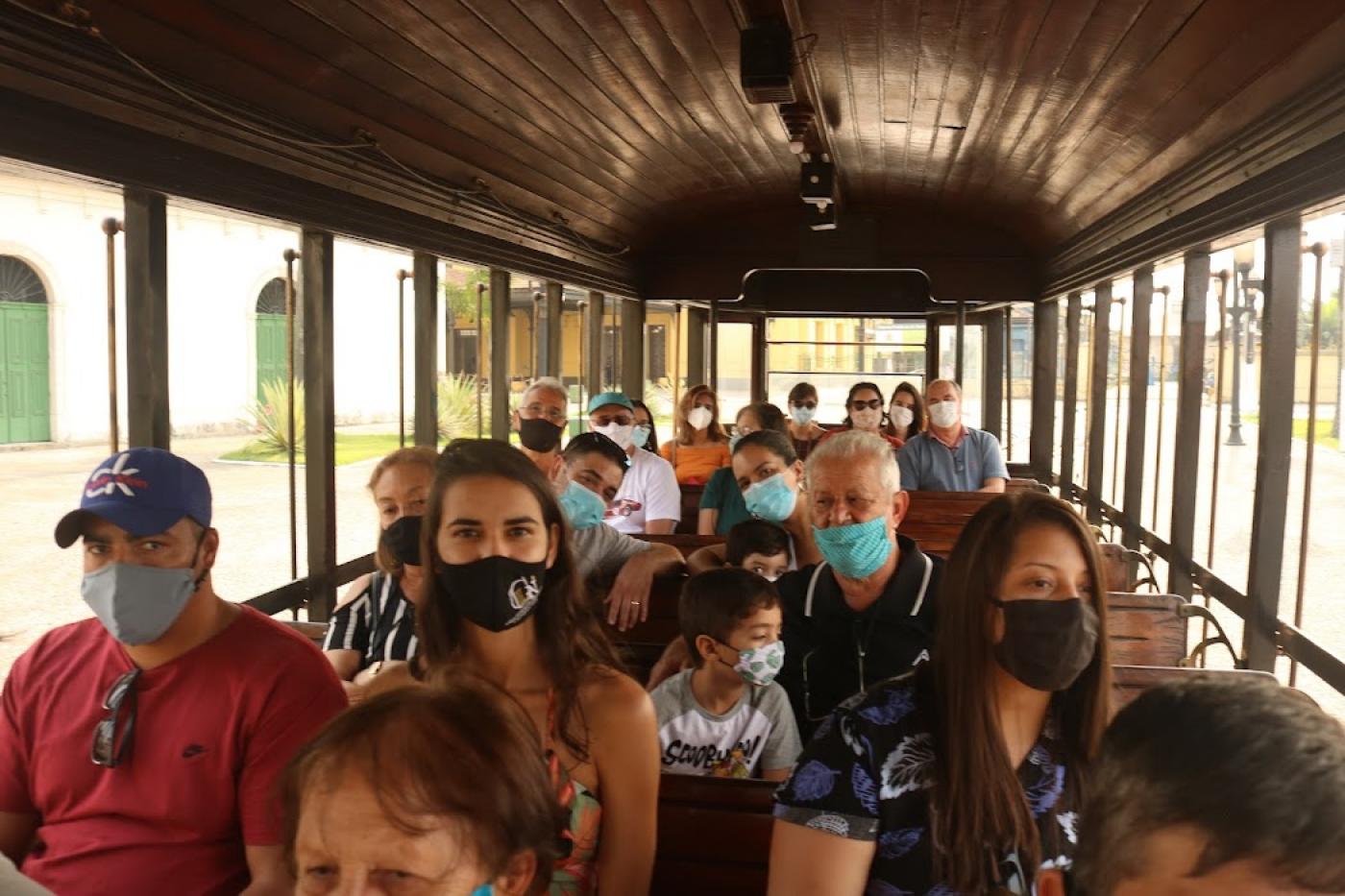 Pessoas sentadas dentro do bonde turístico #paratodosverem