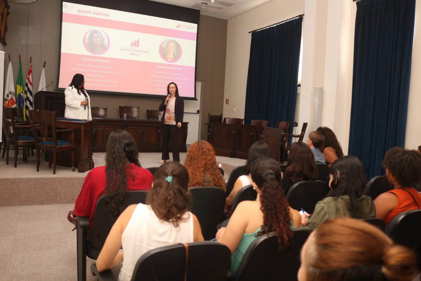 mulheres sentadas em auditório assistem palestra. #paratodosverem 