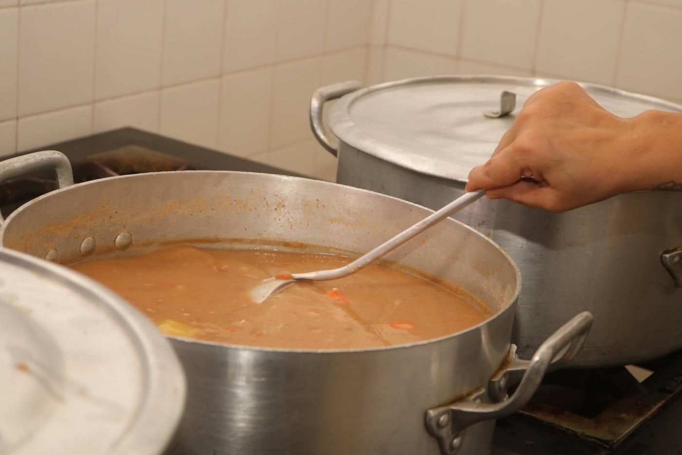 mão mexe em comida dentro de panela. #paratodosverem 