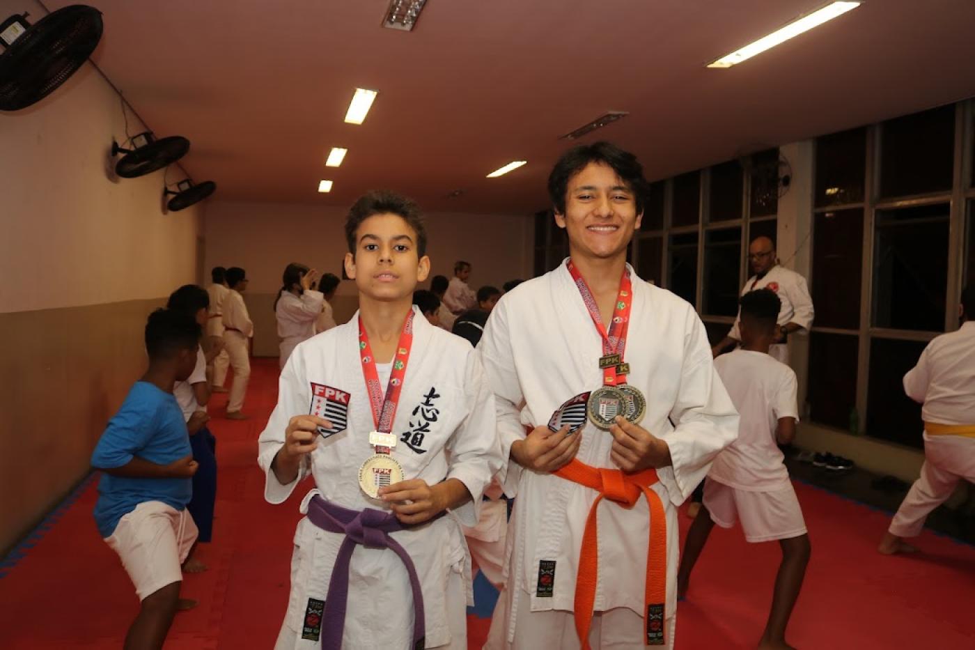 atletas no tatame e com quimono exibem medalhas #paratodosverem