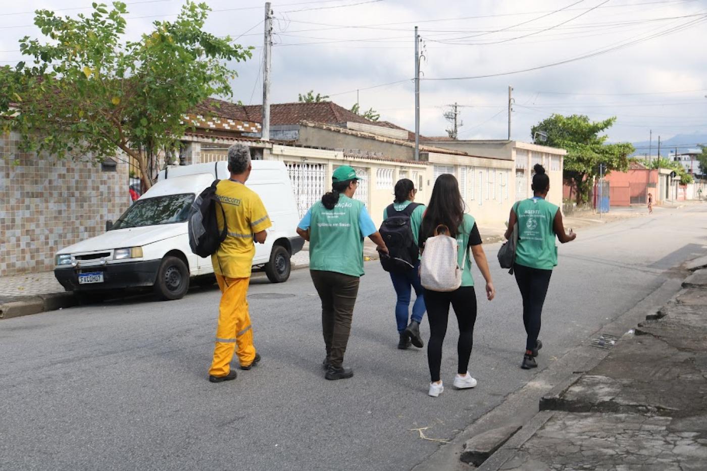 agentes de combate a endemias uniformizados e funcionário da terracom caminham em rua. #paratodosverem 