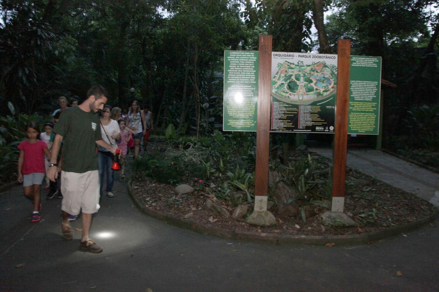 pessoas andando pelo orquidário em visita noturna #pracegover